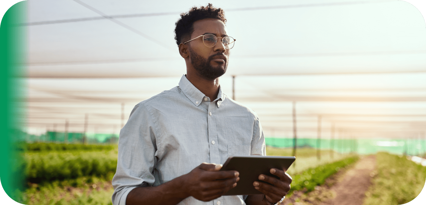 A professional agricultural economist standing in a greenhouse holding a digital tablet, looking focused and ready to apply economic principles to agribusiness.